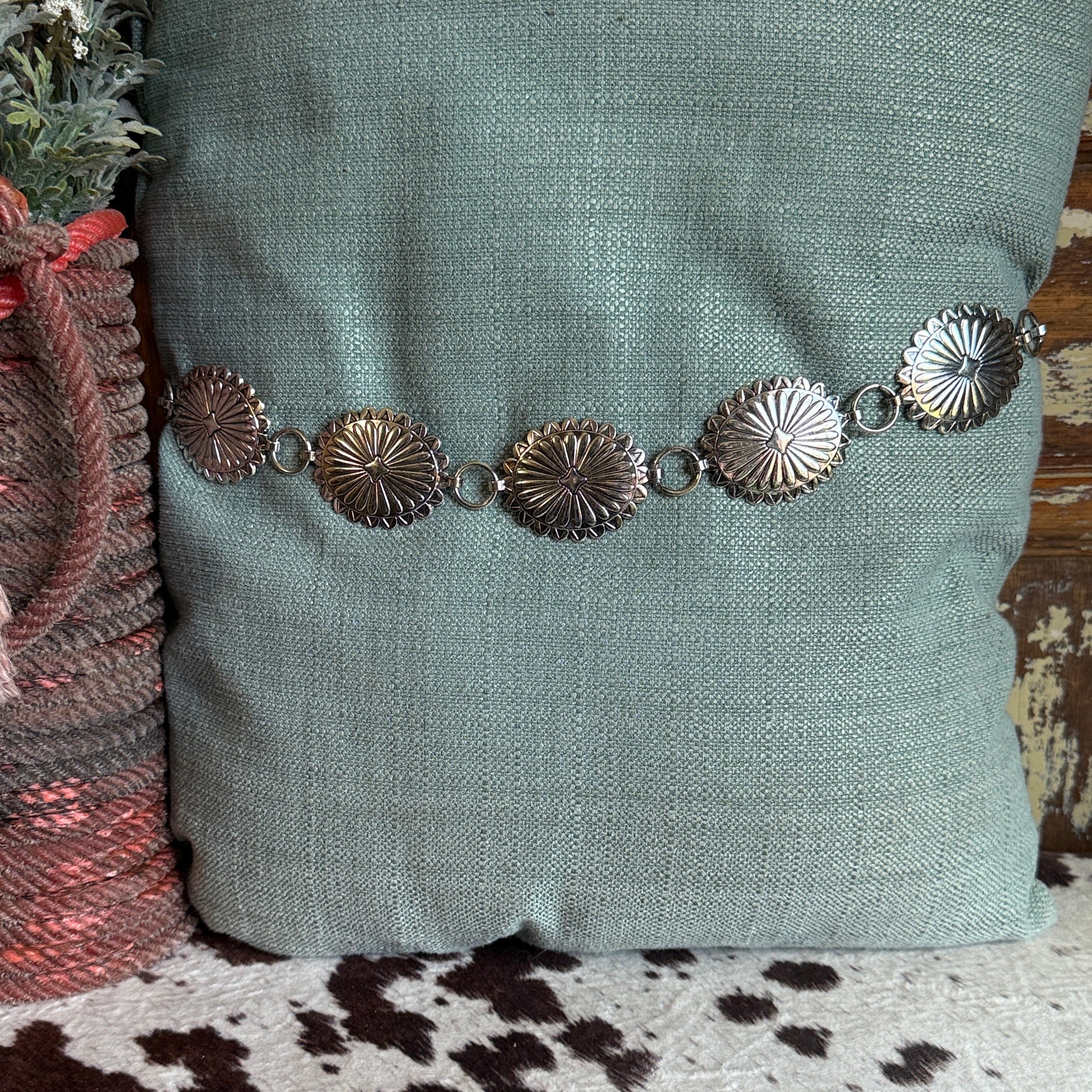 Western concho belt with antiqued silver tone oval scalloped conchos, raised sunburst pattern.