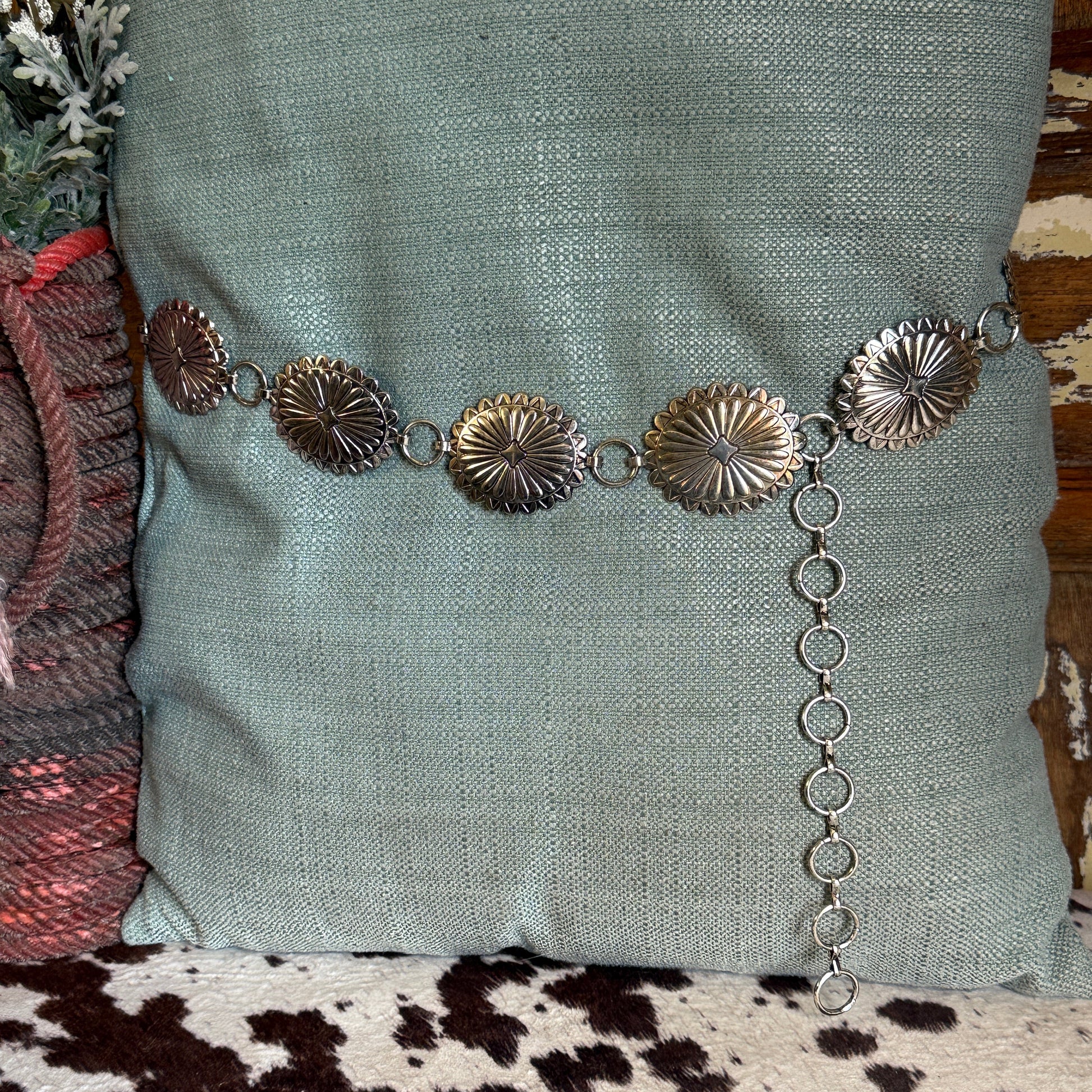 Western concho belt with antiqued silver tone oval scalloped conchos, raised sunburst pattern and chain extender.