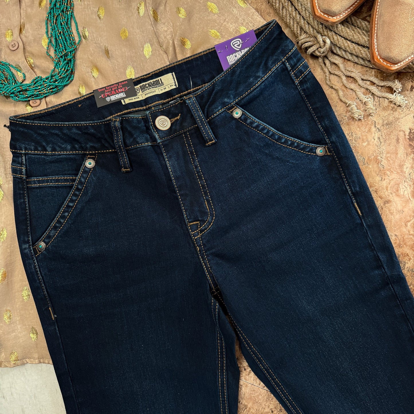Close-up of front pocket with western concho accents and turquoise color stone detail on dark wash denim